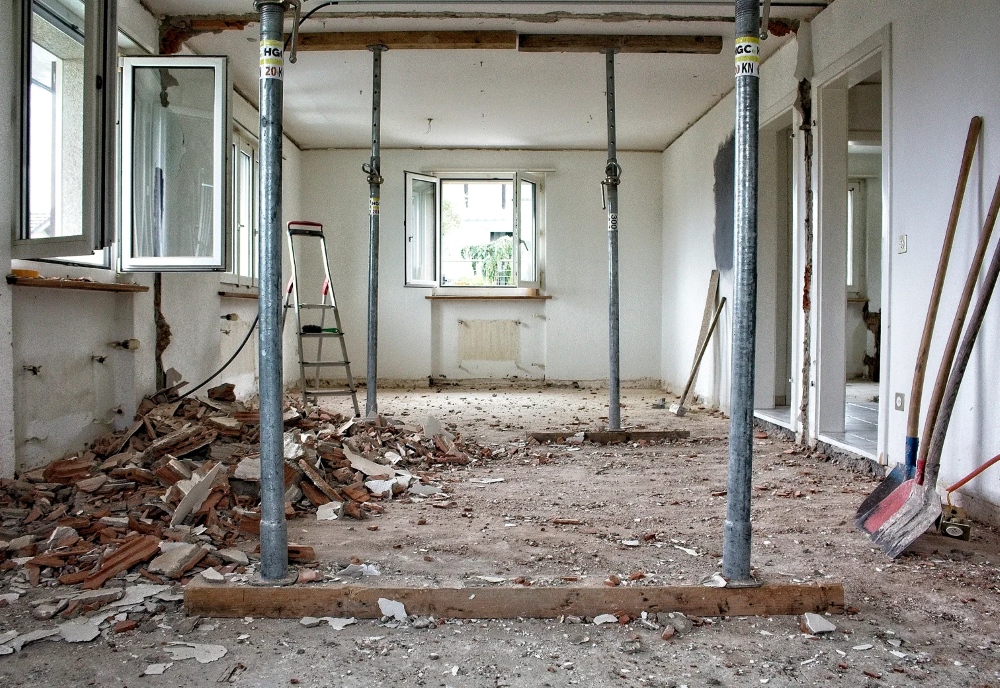 Op de foto zie je een binnenhuisrenovatie waarbij een dragende wand wordt verwijderd en het plafond tijdelijk door stalen stempelpoten wordt ondersteund. Het hoofddoel is het creëren van een open ruimte door veilig een muur weg te halen. De verstelbare stalen stutten dragen kracht tot duizenden kilo’s en bieden een nauwkeurige pasmaat, de werkplek oogt overzichtelijk dankzij direct puinverwijdering en de robuuste poten zijn eenvoudig in hoogte verstelbaar voor verschillende plafondhoogtes.